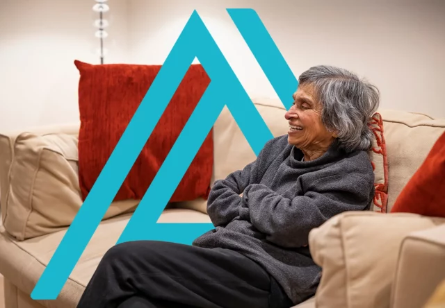 Happy older woman on a couch, symbolising comfort and contentment in well-regenerated housing for older people.
